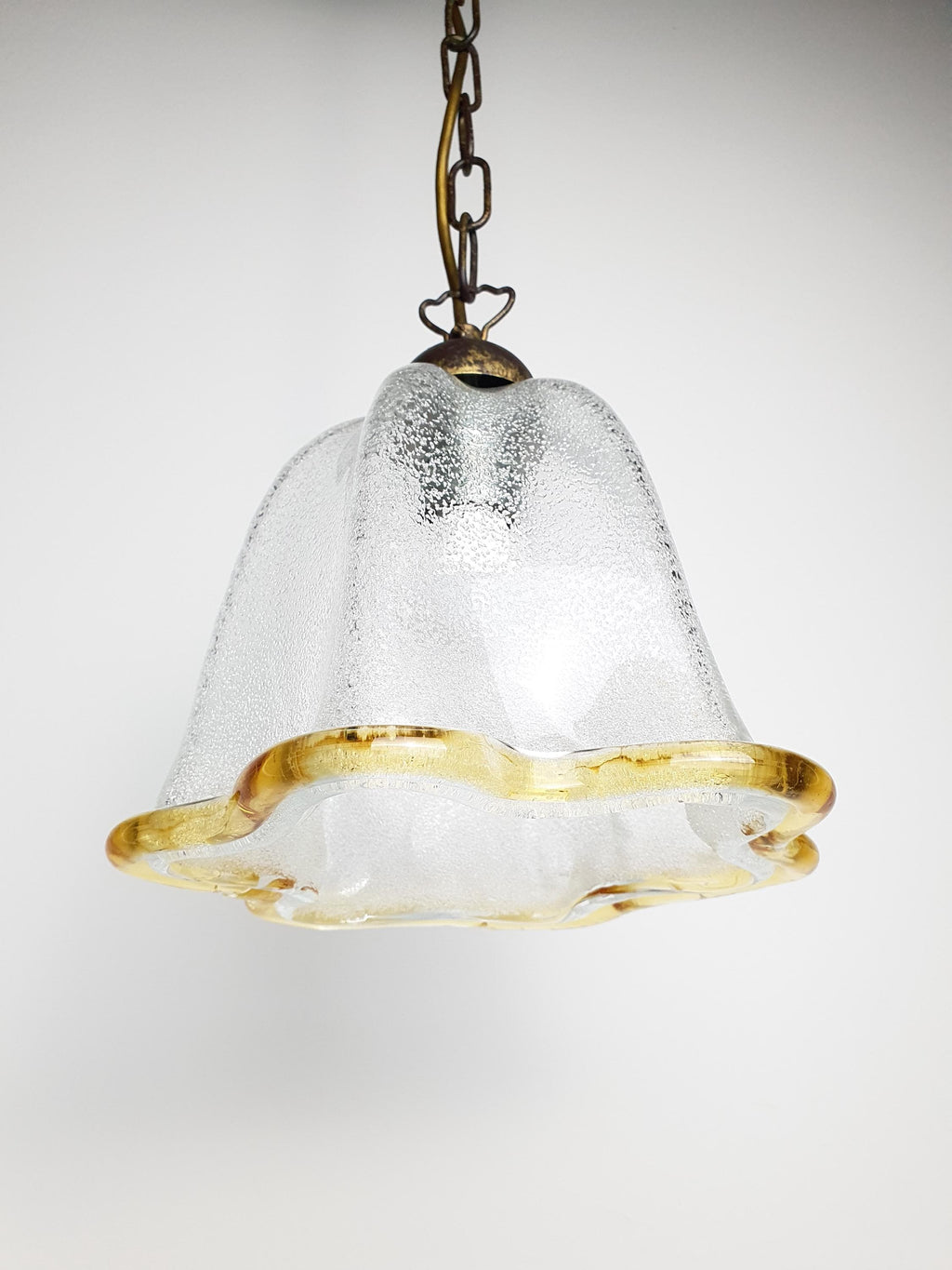 Murano glass bell tulip pendant front view, graniglia icy interior, yellow rim, bronze chain suspension, organic silhouette