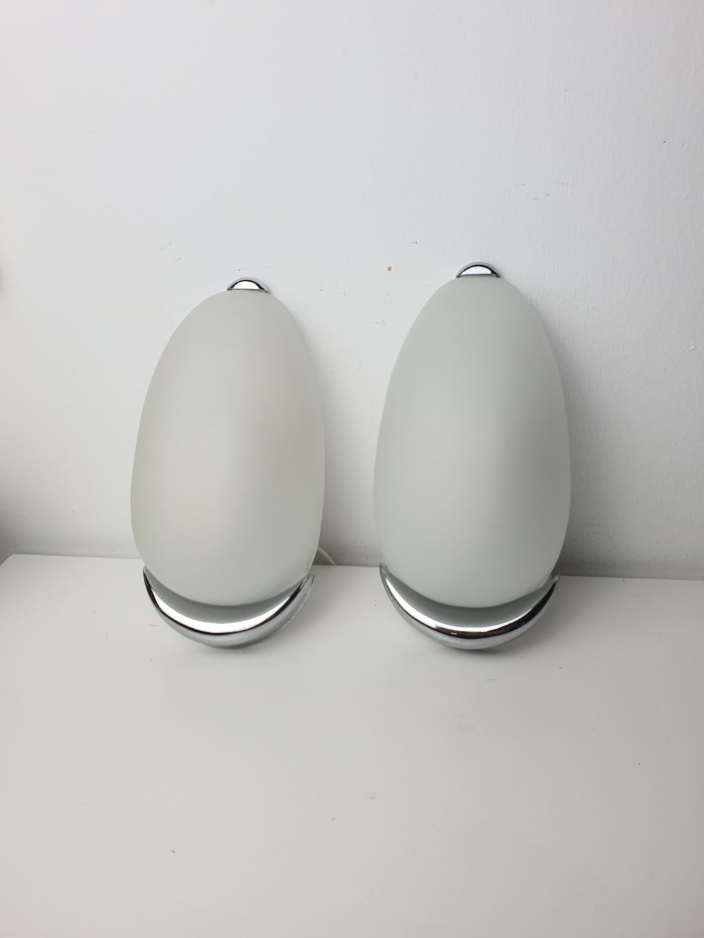 Pair of Italian egg-form sconces in hallway, satin frosted glass capsule shades, balanced symmetrical installation