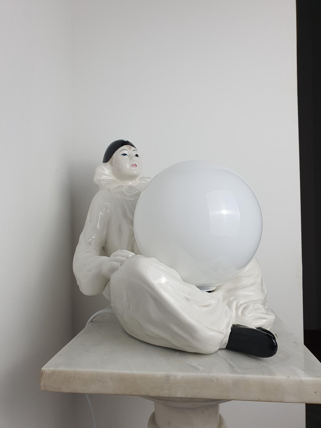 Vintage Italian Pierrot clown ceramic lamp in reading corner, soft atmospheric white globe light, eclectic romantic interior