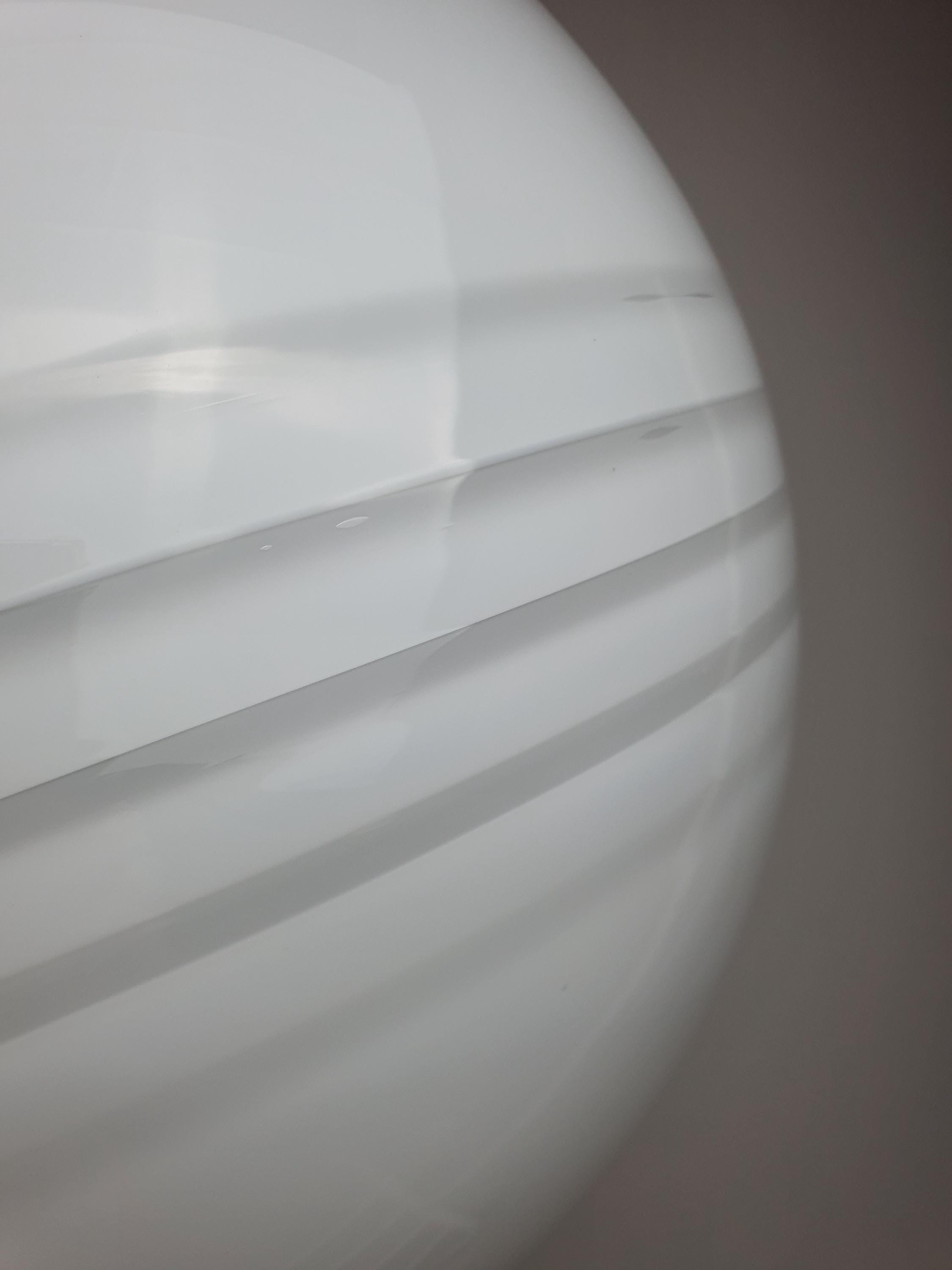 Close-up of white swirl decoration on vintage Murano large glass globe pendant, smooth hand-blown surface texture