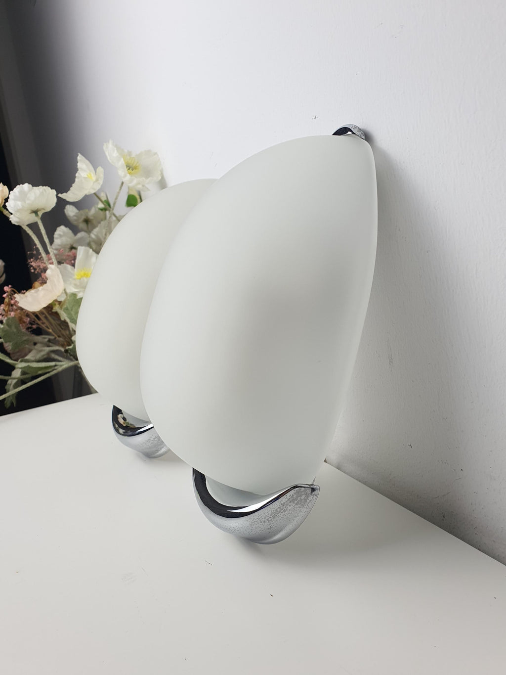 Italian egg-form wall sconce front view, satin frosted glass capsule shade on chrome base, minimalist design