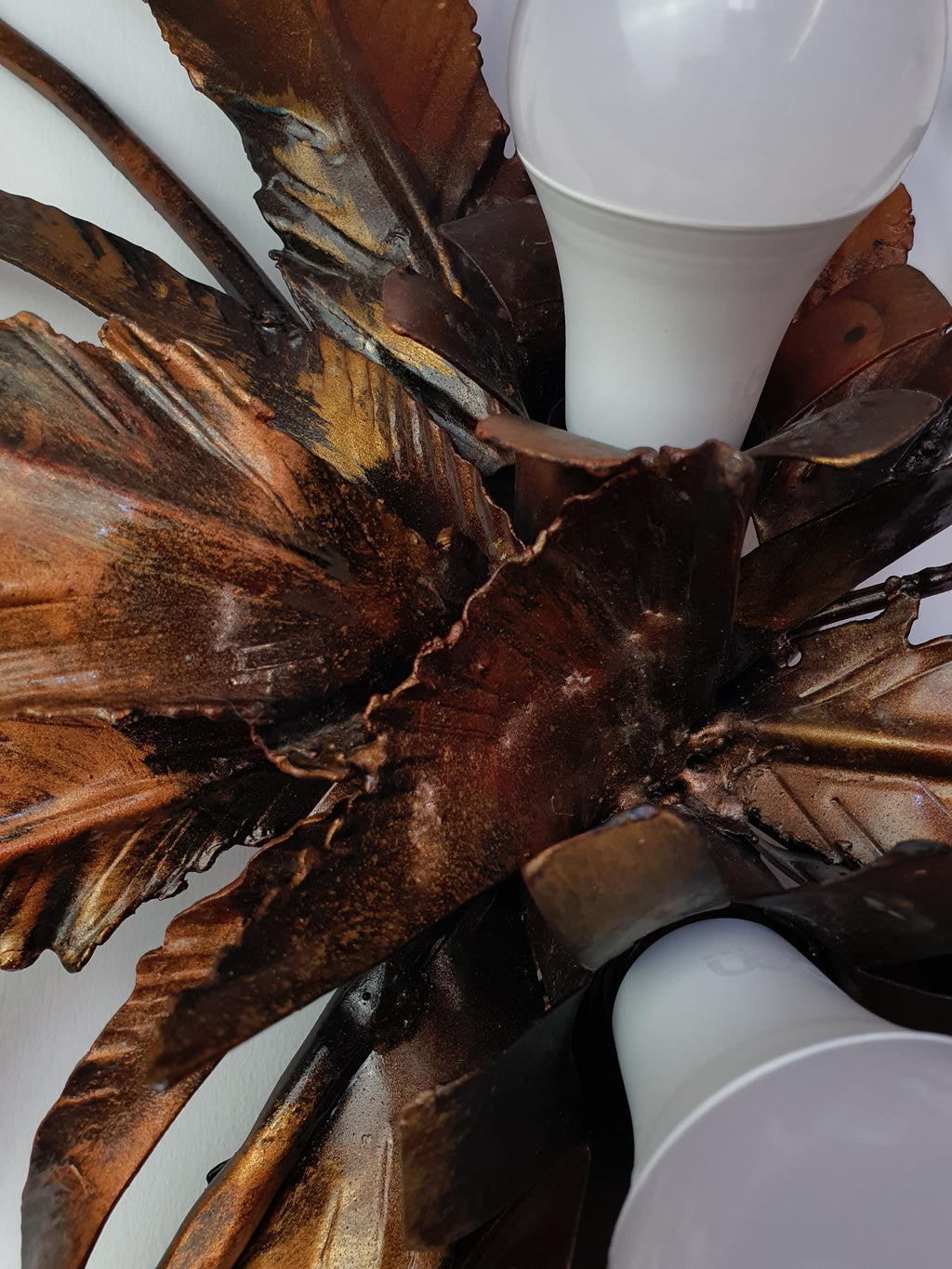 Age-related patina and finish variations on vintage gilded metal foliage
