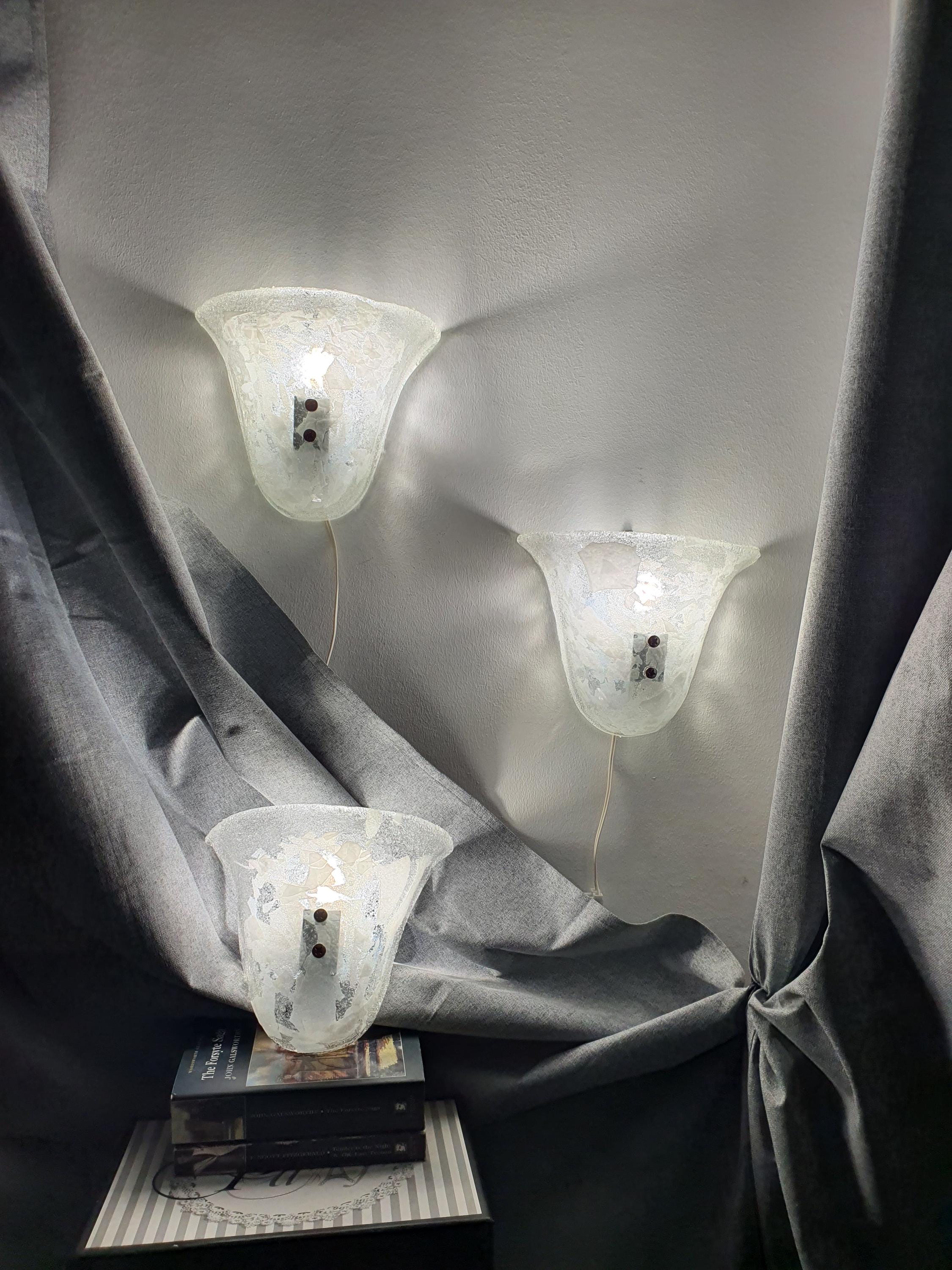 Set of 3 Murano glass shell sconces lit, soft diffused glow through clear and white inclusion glass, hallway installation