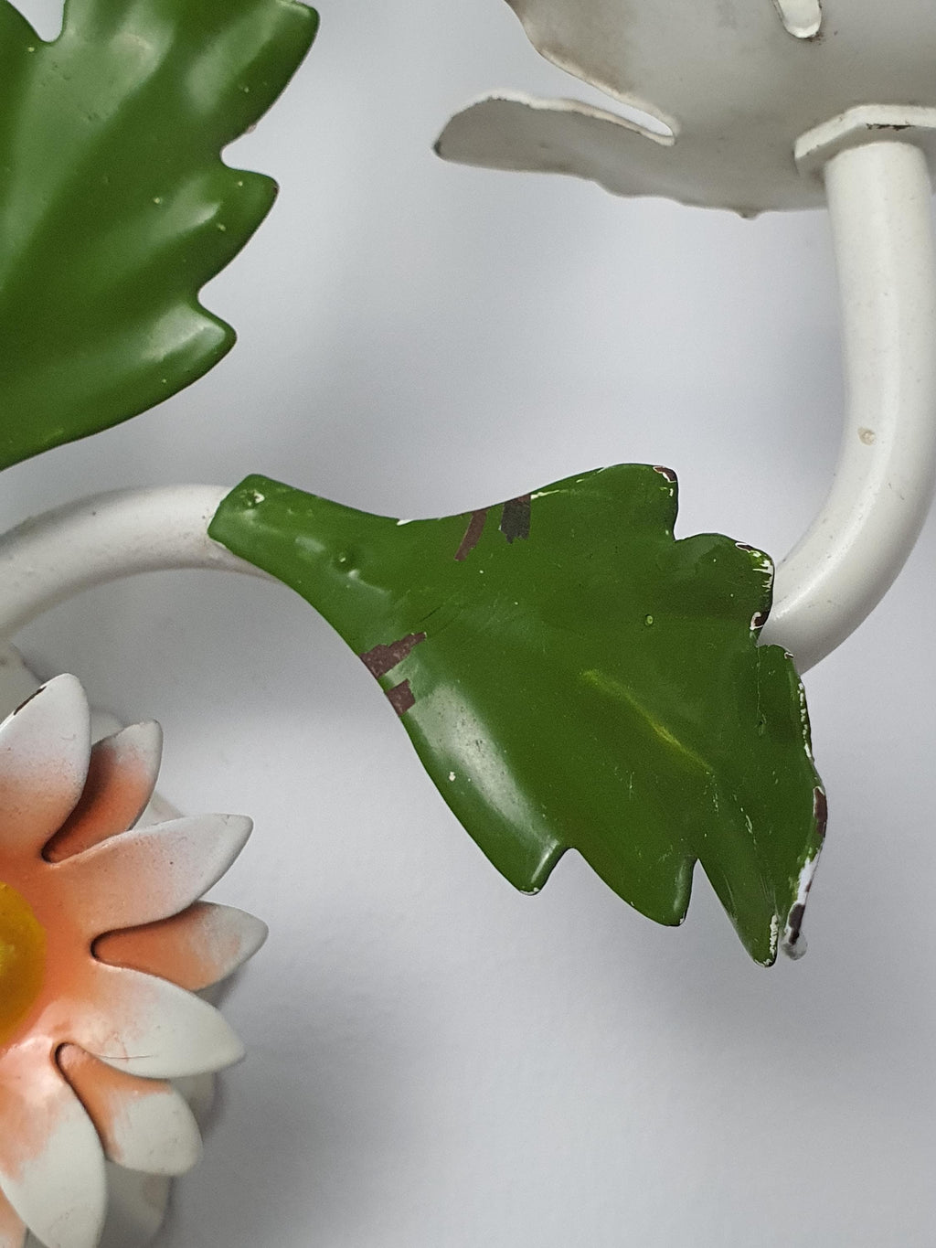 Close-up of white green orange painted metal flowers on vintage 1970s Italian tole wall sconce, handcrafted floral detail