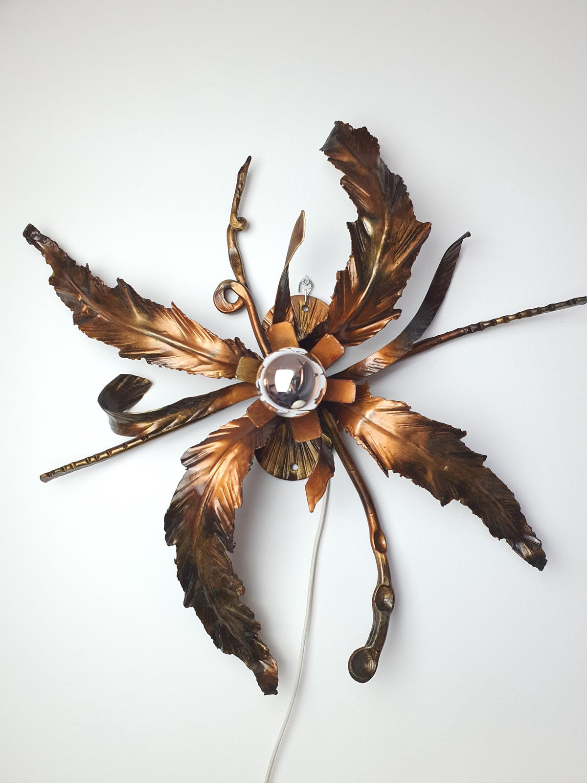 Age-related wear on the metal surface of a vintage leaf-shaped fixture
