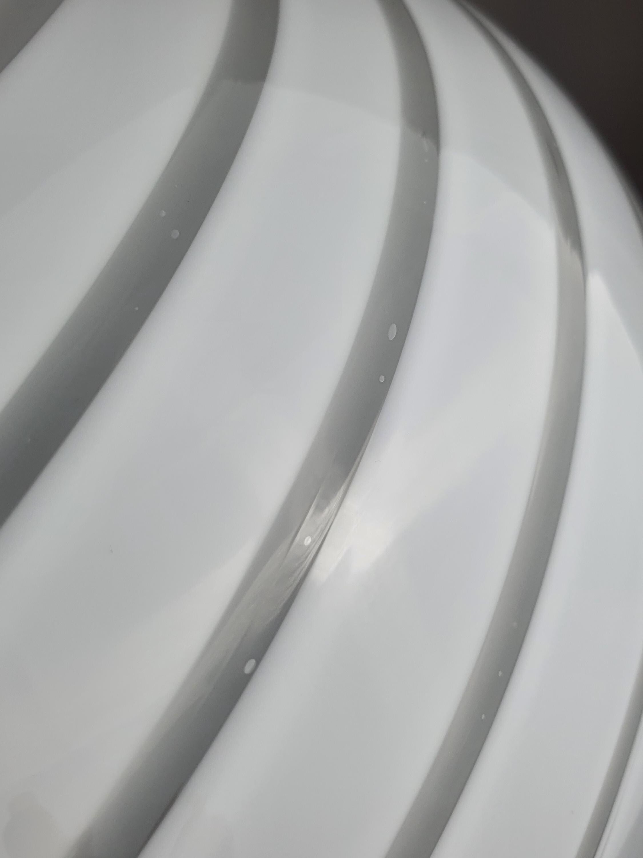 Close-up of delicate white swirl decoration on vintage Murano glass globe pendant, soft light diffusion texture