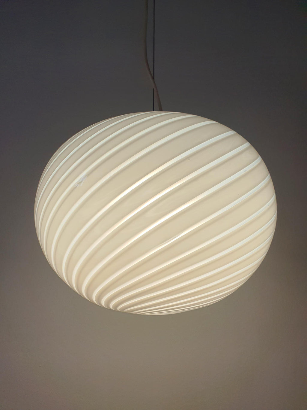Vintage Murano white swirl globe pendant in bedroom, soft white swirl glow, understated elegant Italian lighting