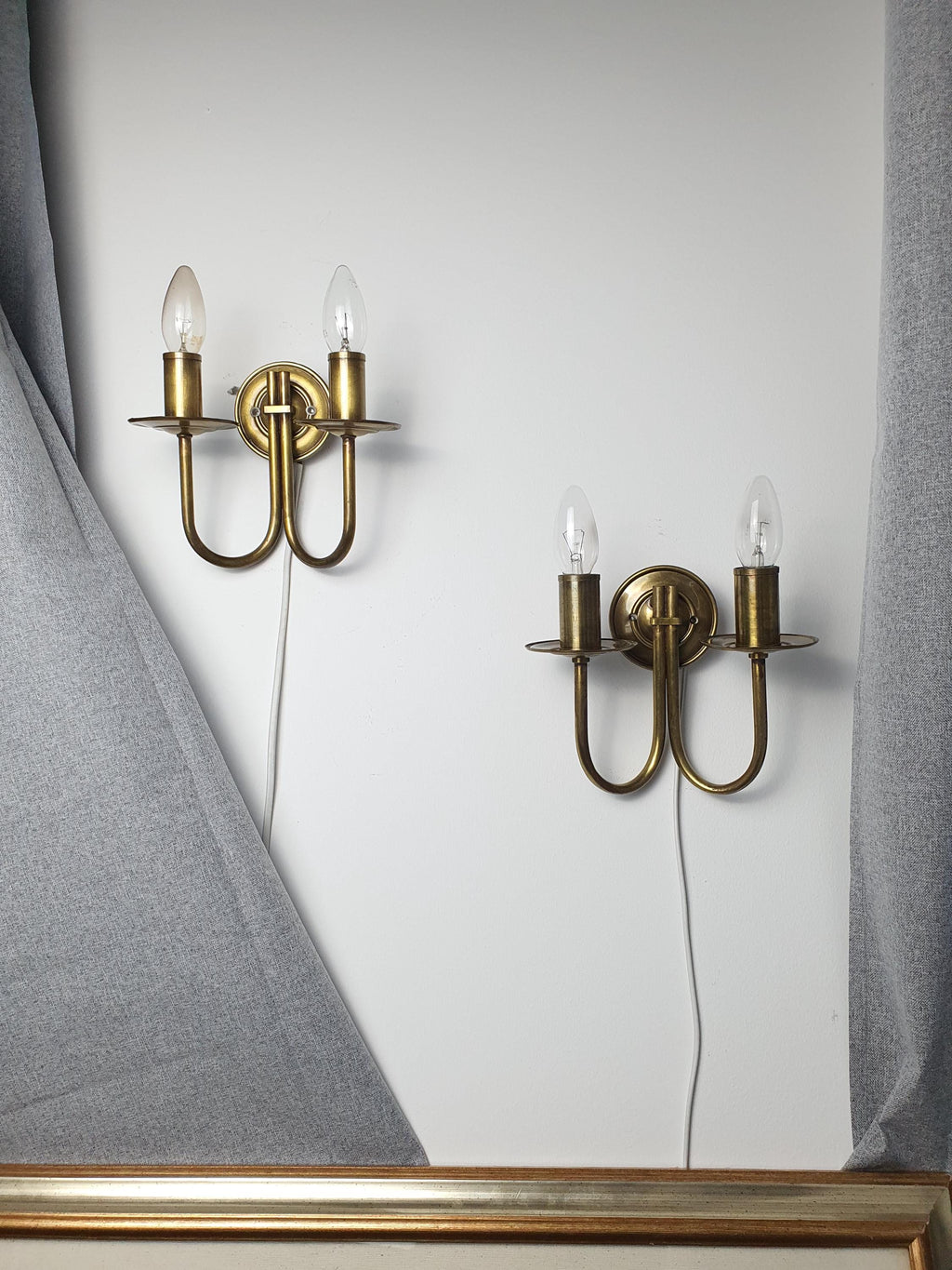 Pair of vintage Italian double-arm lacquered brass wall sconces lit, warm brass glow, two E14 arms, Hollywood Regency interior