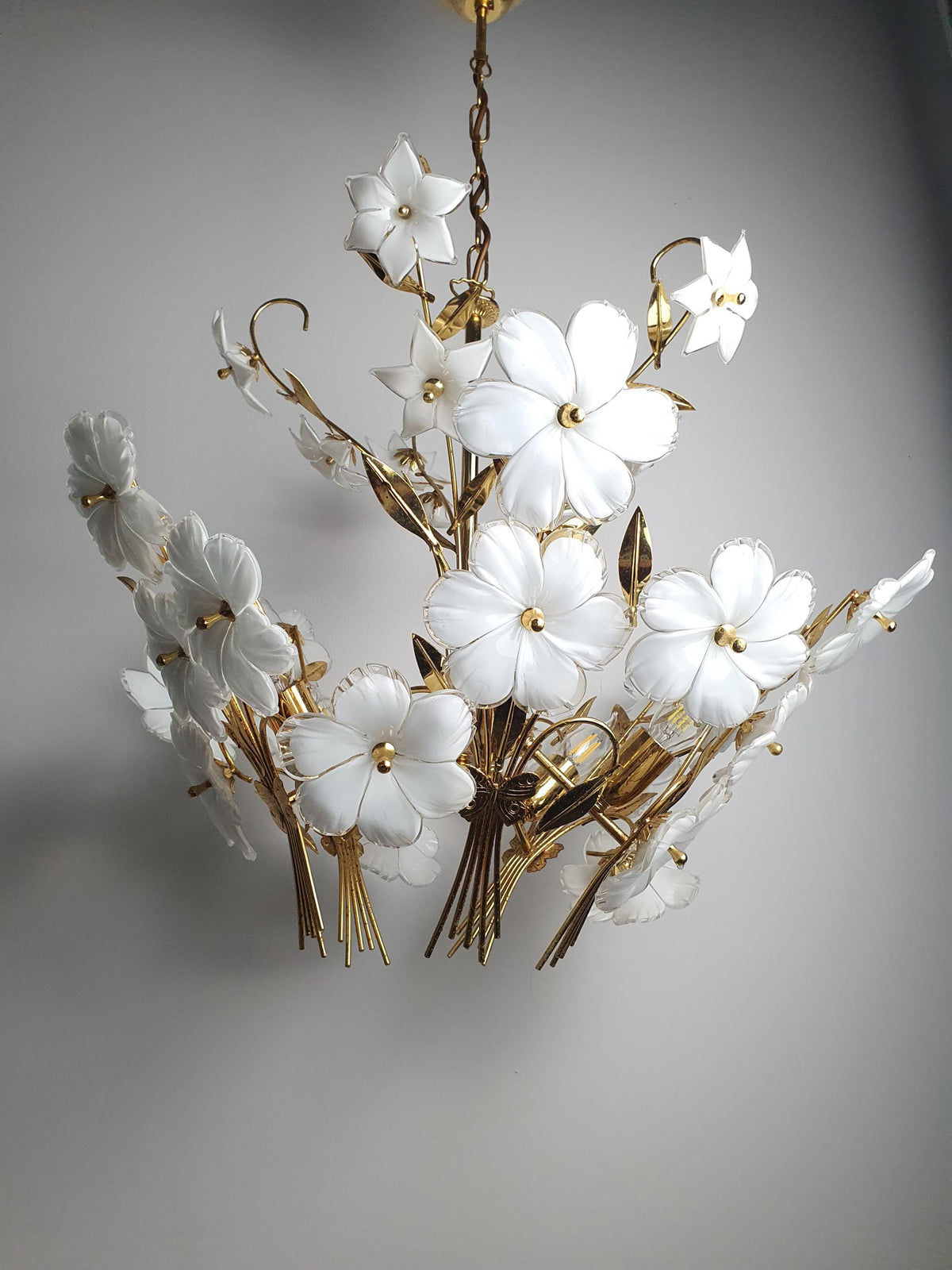 Vintage 1980s Murano glass floral chandelier illuminated, soft glow through white ribbed flowers, gold-tone botanical bouquet