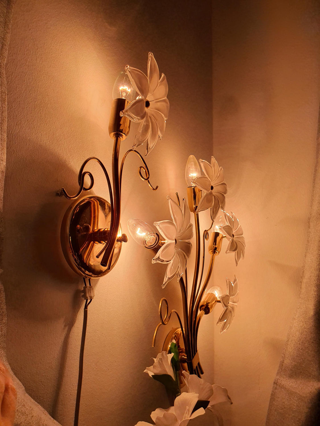 Vintage Italian Murano glass floral wall sconces lit, soft milky white glass flower glow, gold-toned metal frame, romantic interior