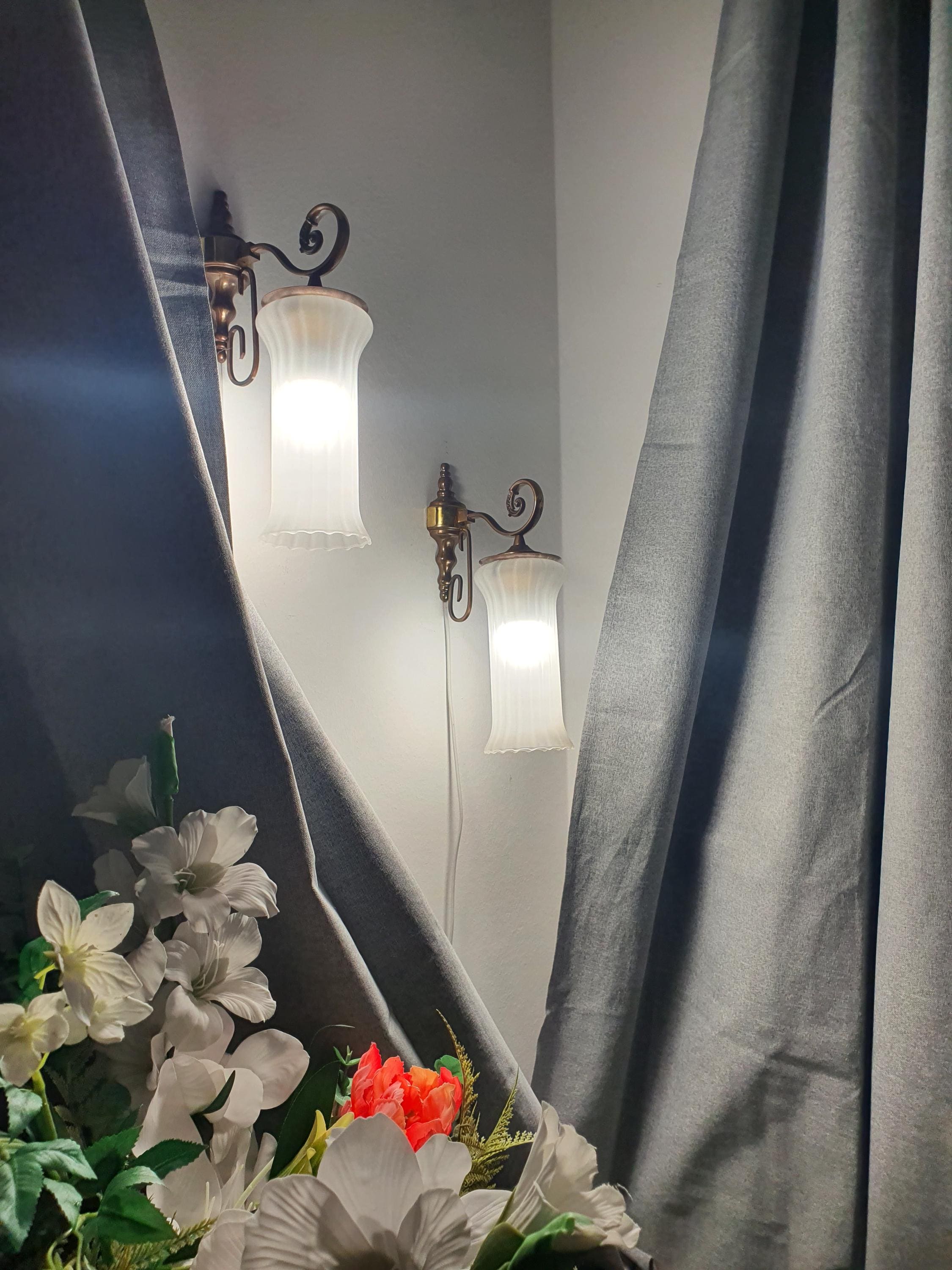 Pair of vintage Italian satin frosted flute wall sconces lit, warm soft ambient glow, brass bases, classical hallway setting
