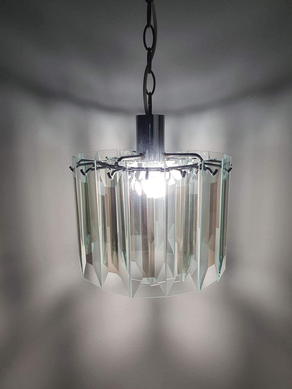 Vintage Art Deco chandelier in dressing room, crystal glass petal glow, aged chrome, compact MCM geometric statement