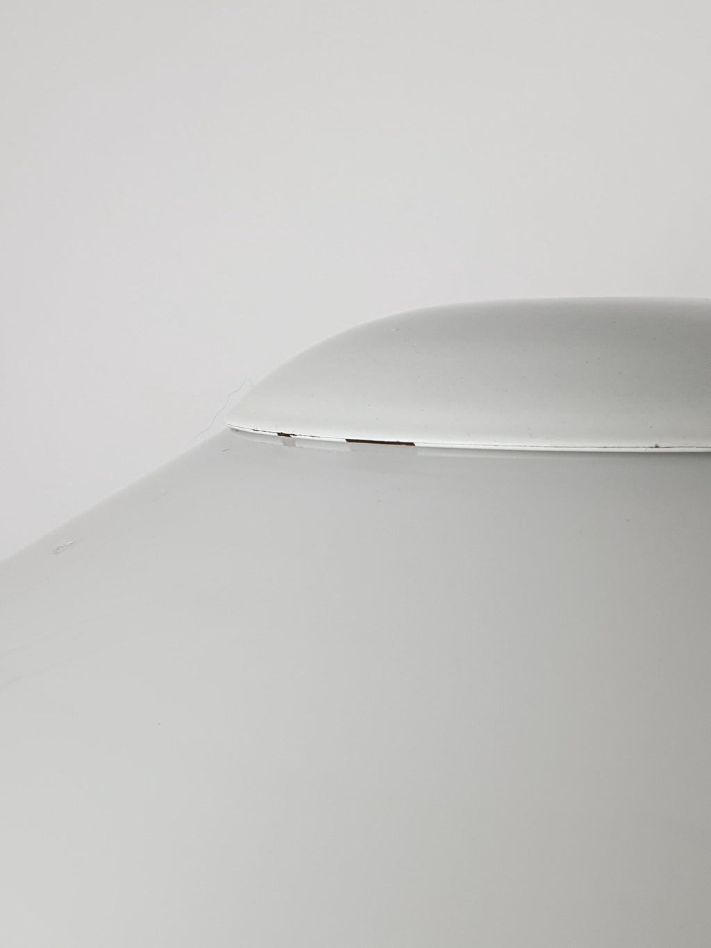 Close-up of the white glass shade rim, showing a small chip along the edge, part of the vintage condition noted in the listing.