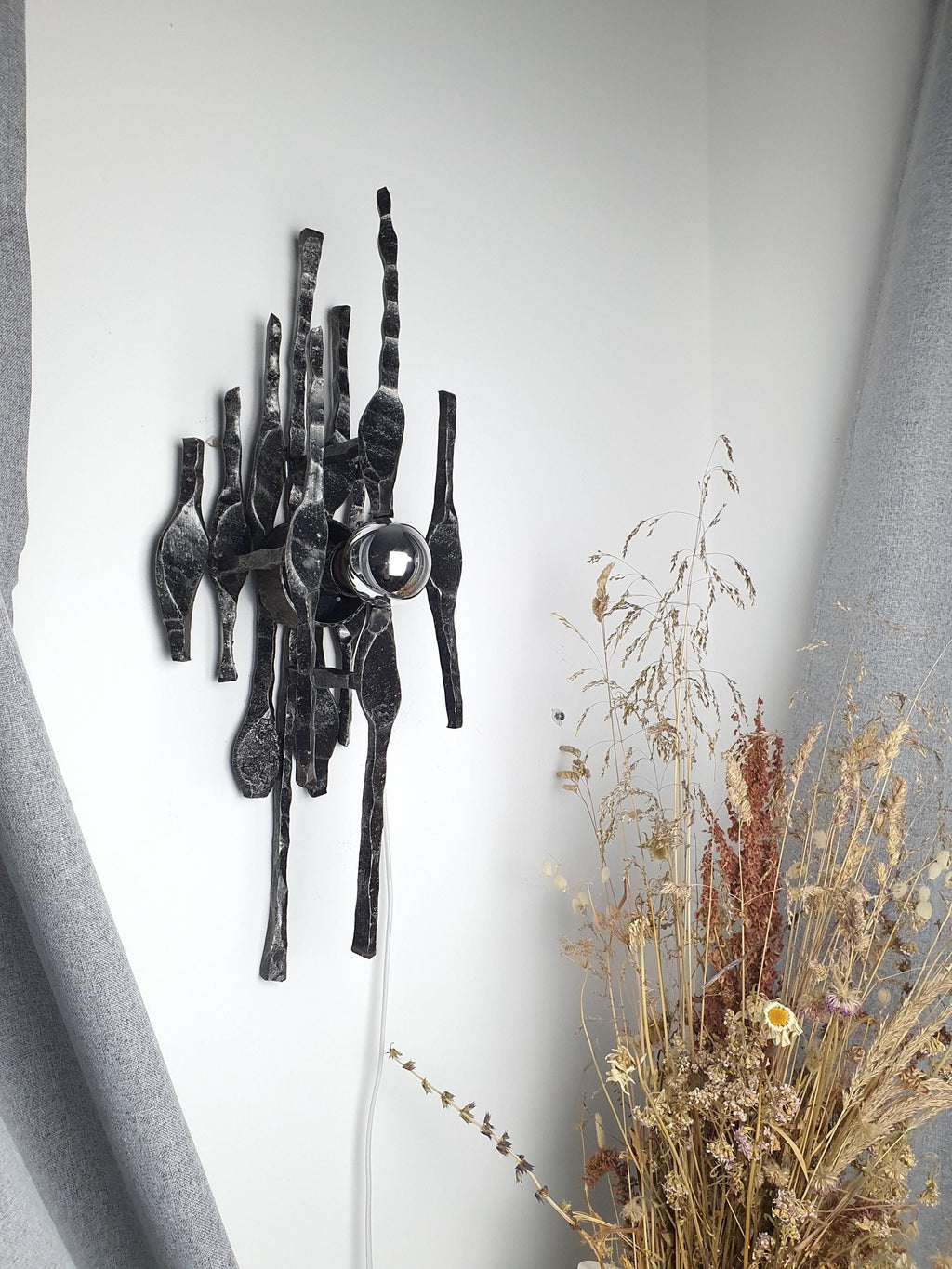 Vintage Brutalist iron wall sconce installed in hallway, architectural statement piece