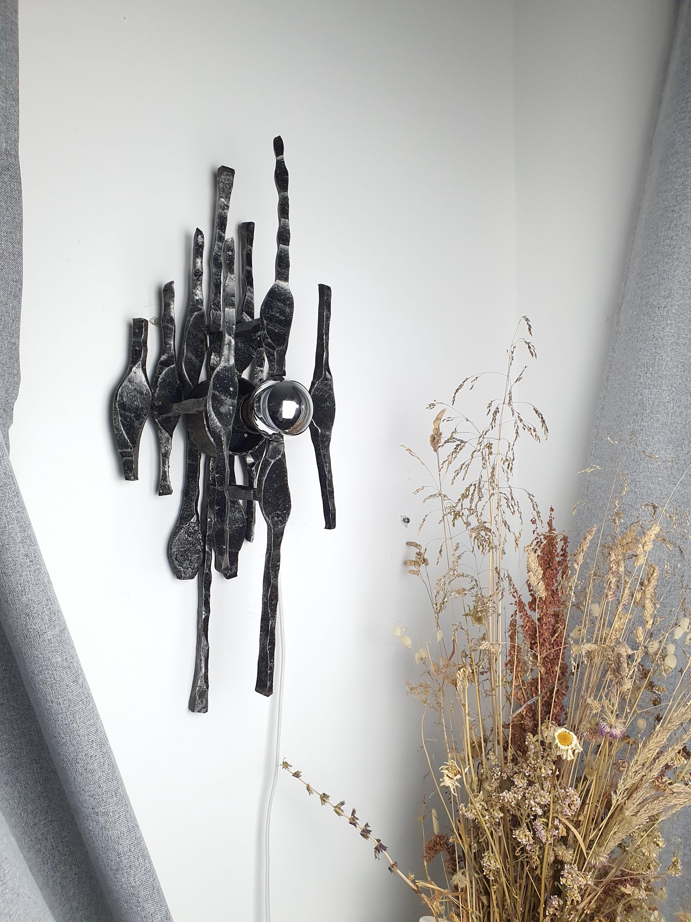 Vintage Brutalist iron wall sconce installed in hallway, architectural statement piece