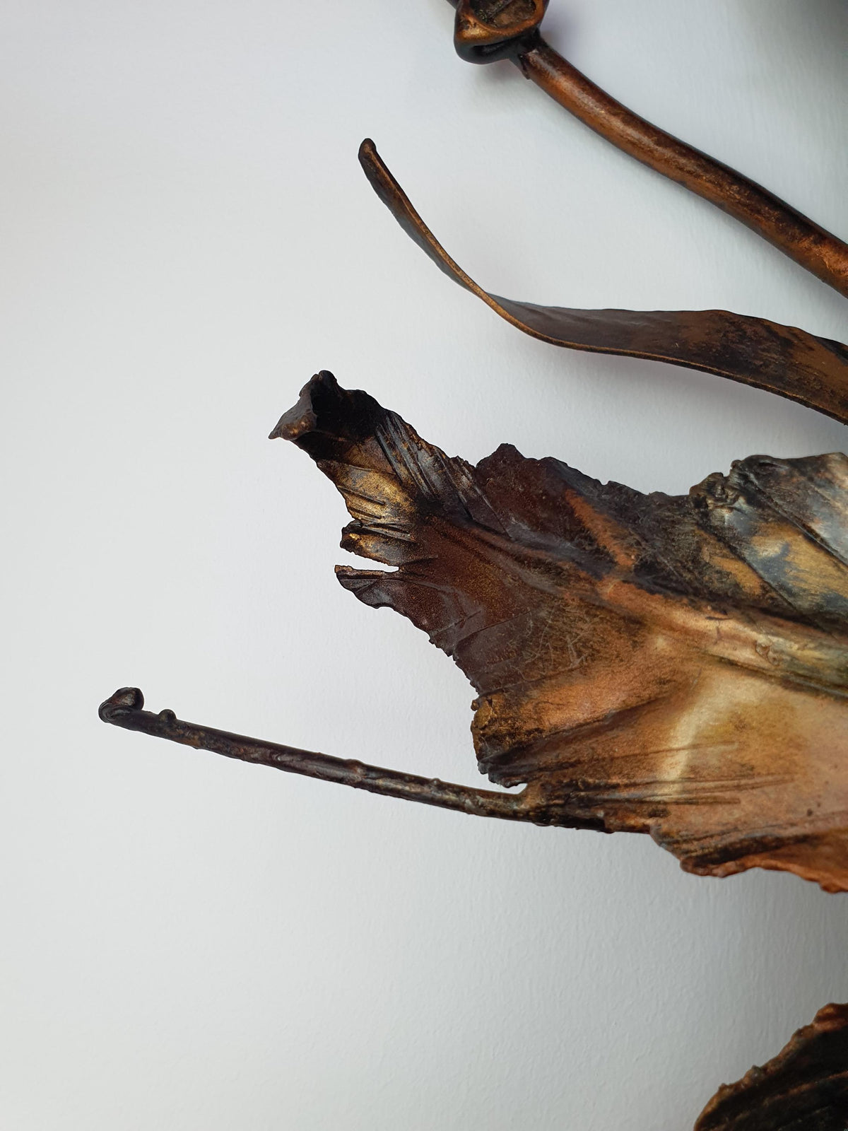 Bronze and gold tones on handcrafted metal leaves of a vintage botanical light
