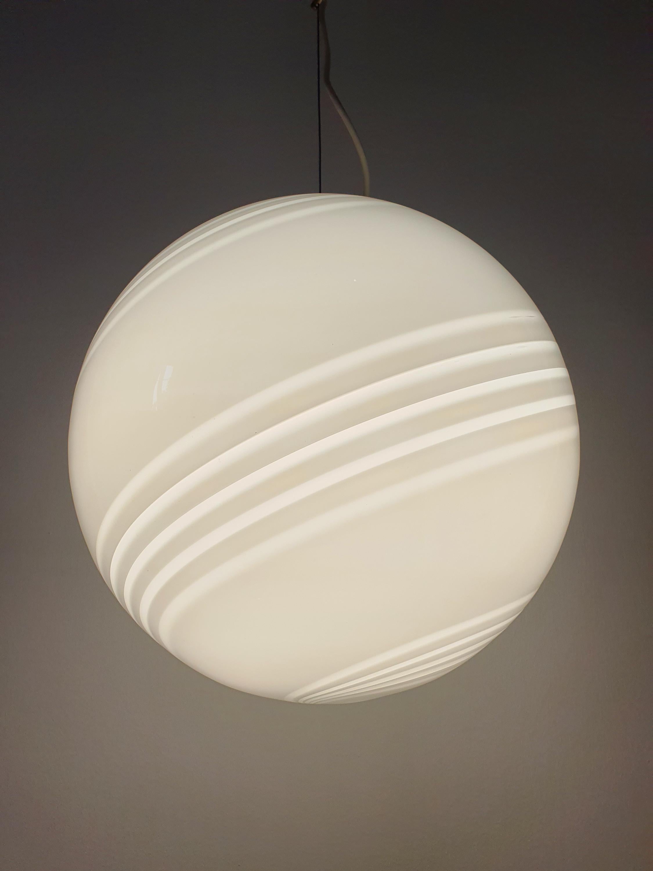 Vintage Murano large white swirl globe pendant lit, soft warm diffused glow through white swirl glass, dining room setting