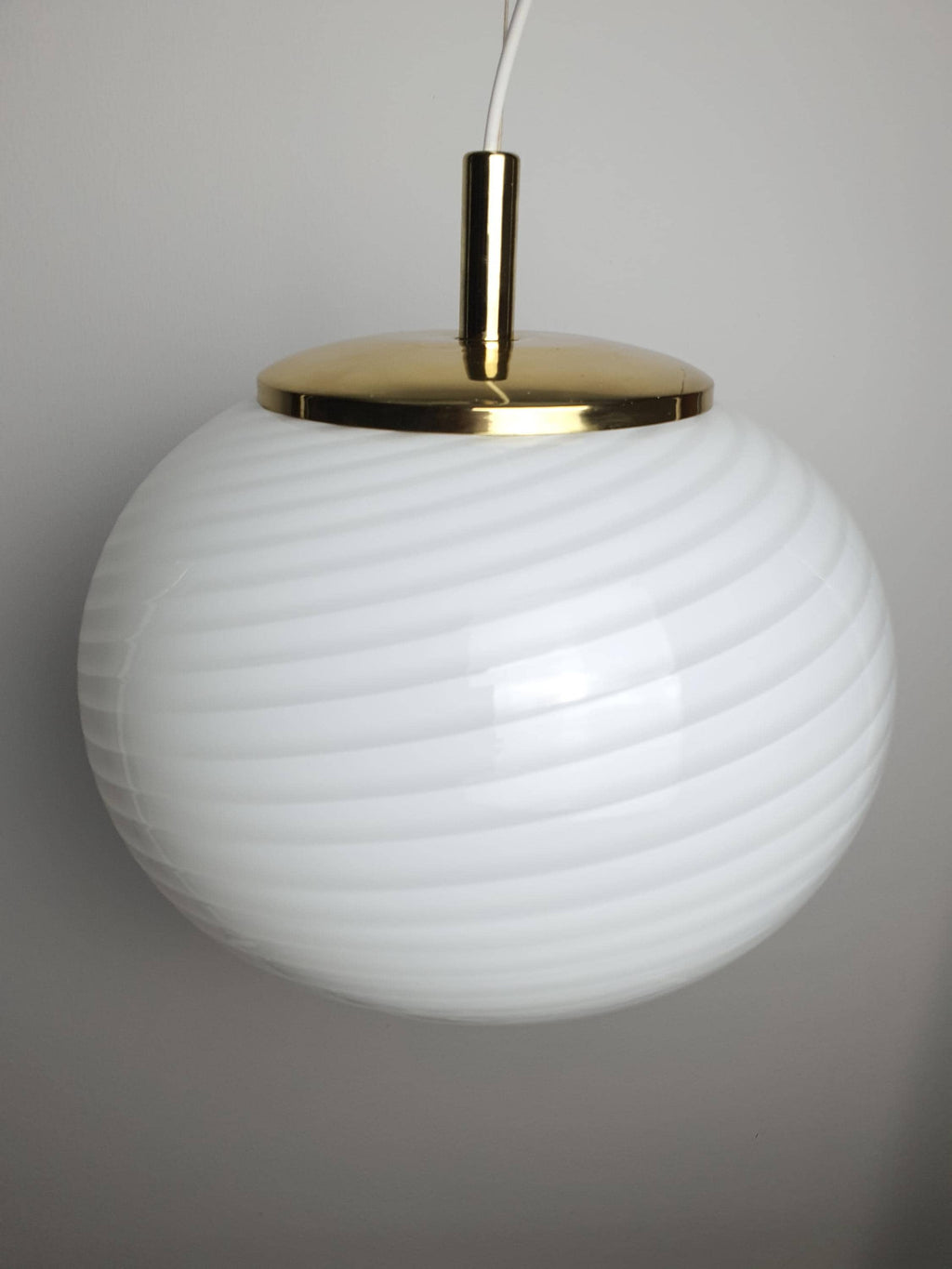 Vintage Murano globe pendant combining white swirl glass and warm brass tones
