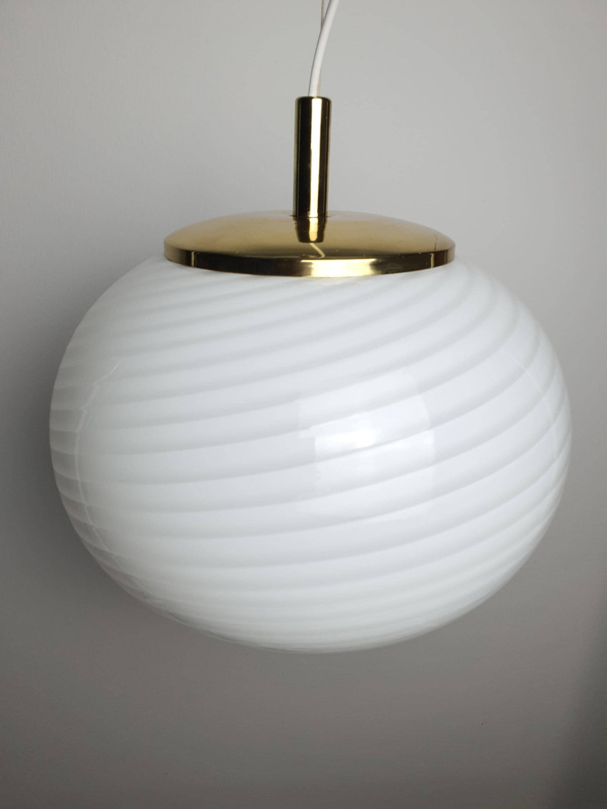 Vintage Murano globe pendant combining white swirl glass and warm brass tones
