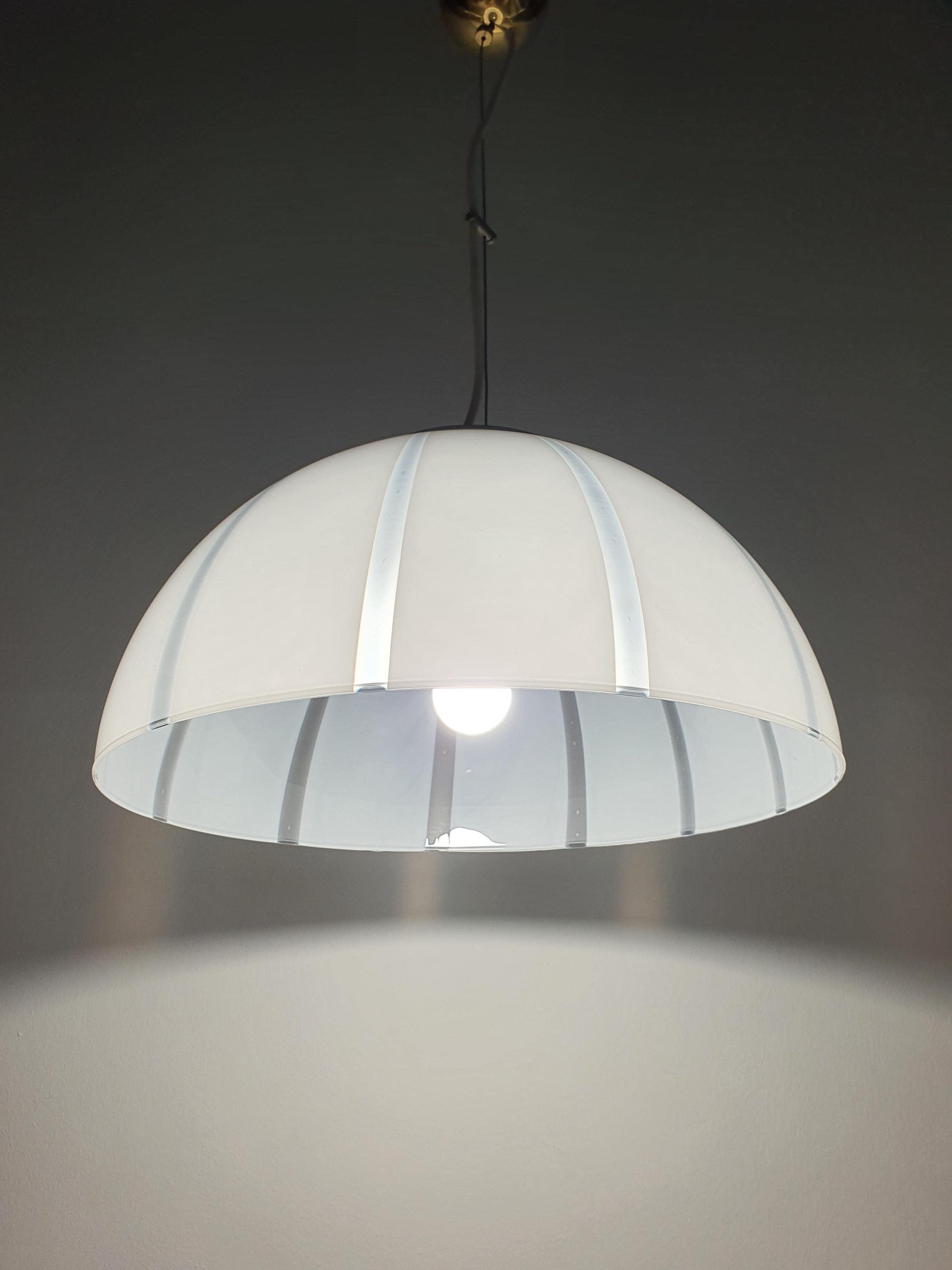 Vintage Murano bell pendant lit, soft warm diffused glow through white and clear striped glass, dining room setting