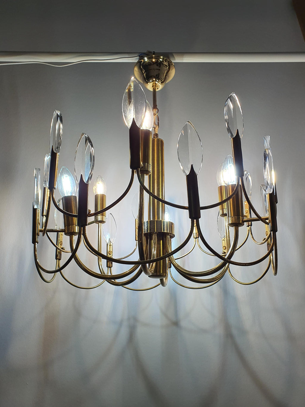 Vintage Sciolari-style brass chandelier lit, dazzling crystal reflections, warm golden glow, Hollywood Regency interior