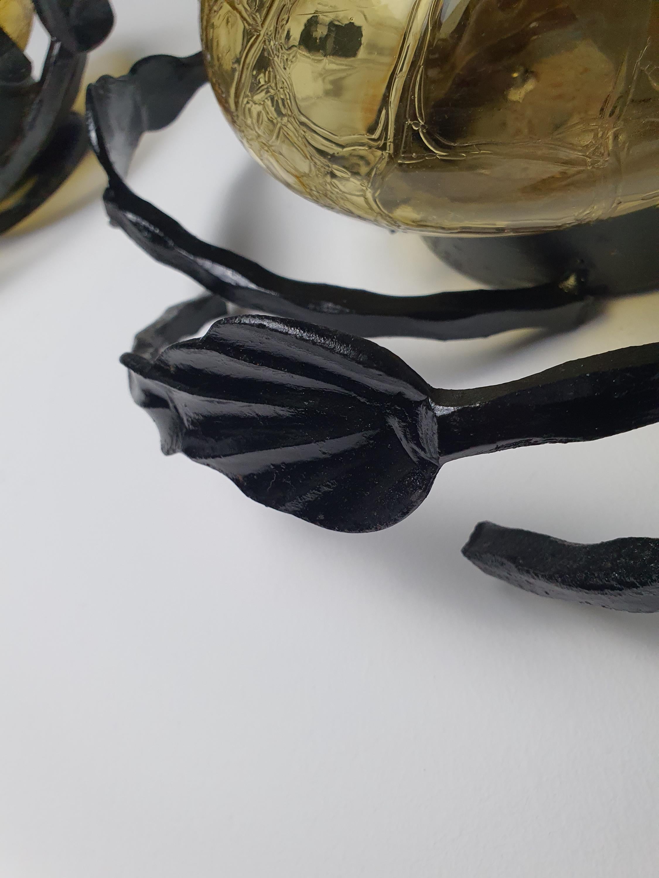 Sculptural leaf and branch detail on vintage 1970s Brutalist black wrought iron wall sconce frame, honey amber glass

