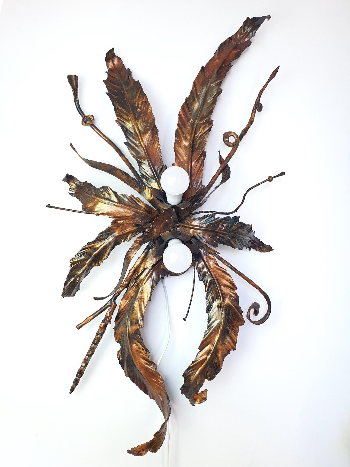Vintage botanical light with layered metal leaves and branches in bronze and gold tones
