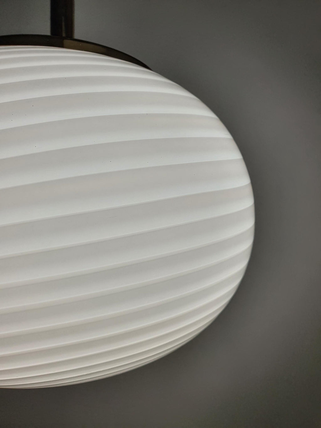 Rounded glass shade with flowing white swirl details on a vintage Italian pendant
