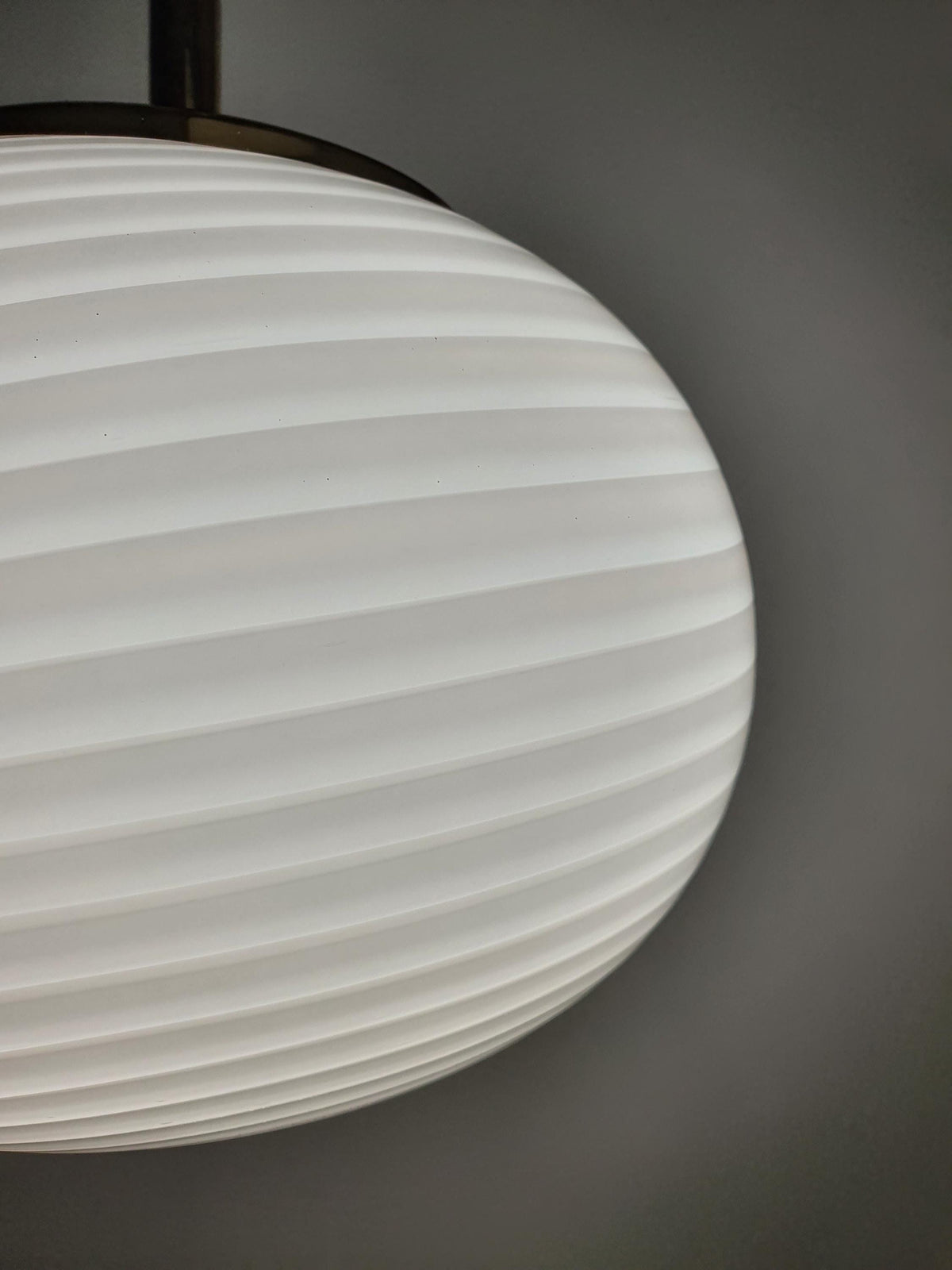 Rounded glass shade with flowing white swirl details on a vintage Italian pendant
