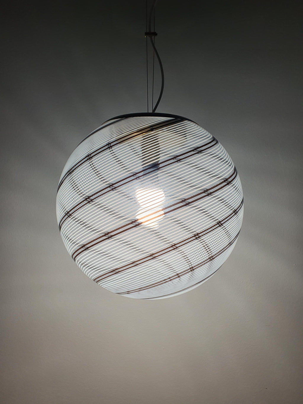 White and brown linear glass decoration wrapping around a globe shade
