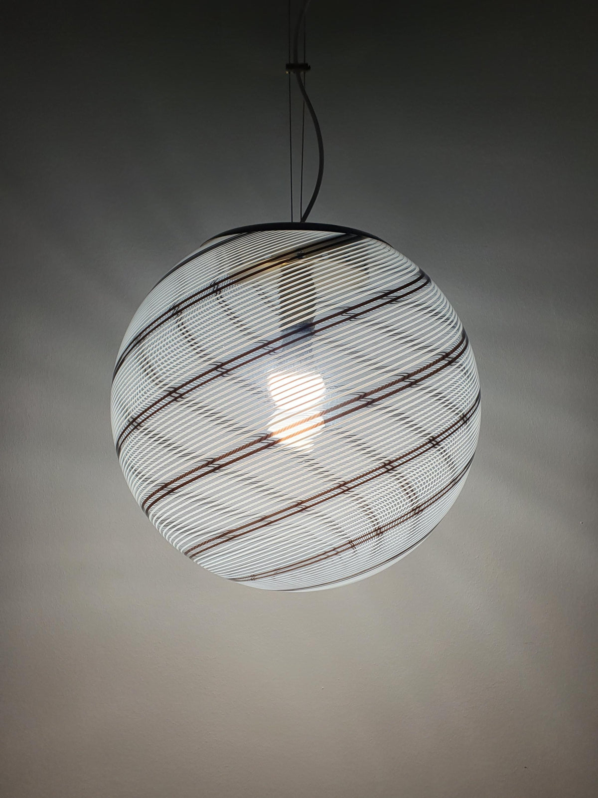 White and brown linear glass decoration wrapping around a globe shade
