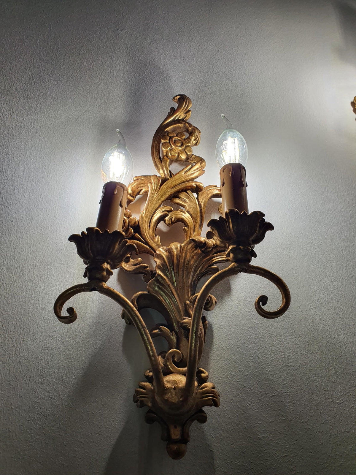 Curved candle arms extending from a carved wooden wall sconce

