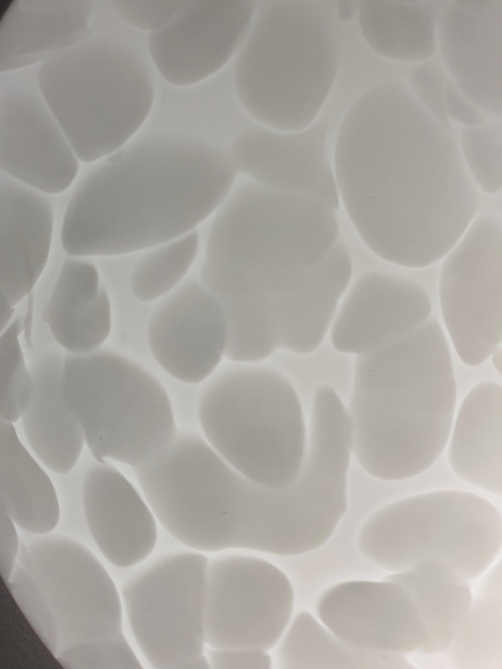 Close-up of irregular white spots in layered clear Murano glass flush mount shade, moonstone texture
