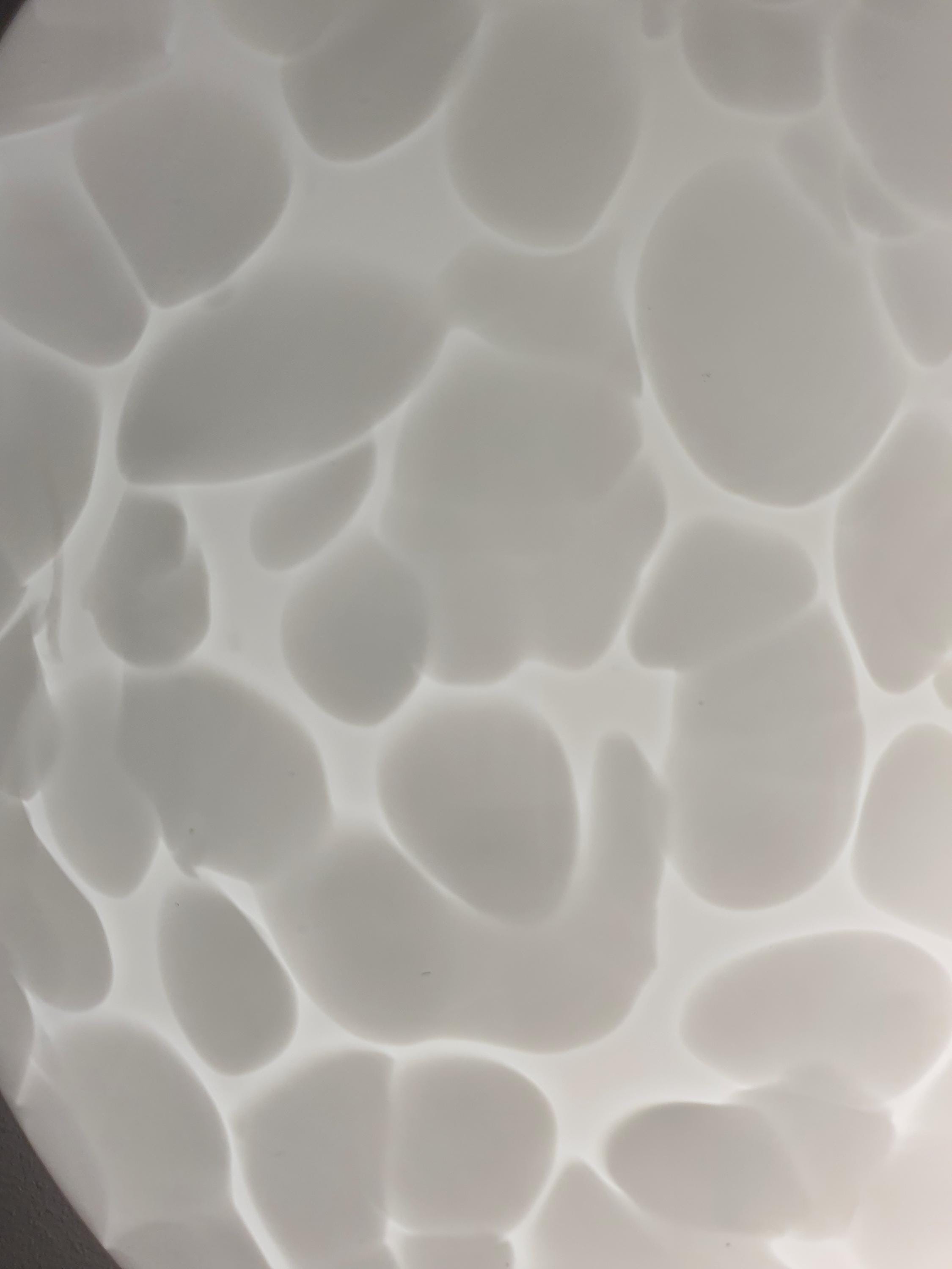 Close-up of irregular white spots in layered clear Murano glass flush mount shade, moonstone texture