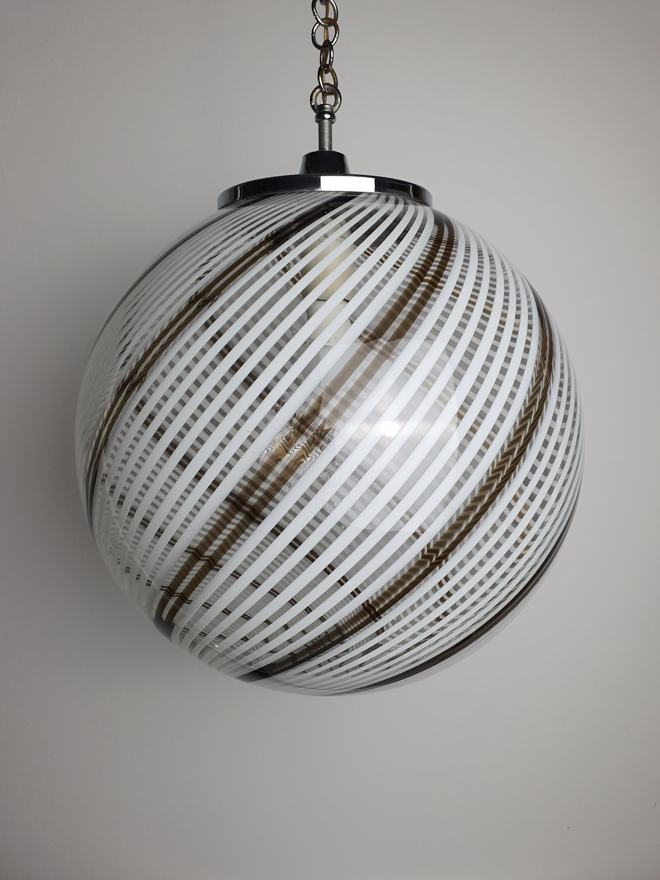 Close-up of white and brown filigrana swirl lines suspended in vintage Murano glass globe