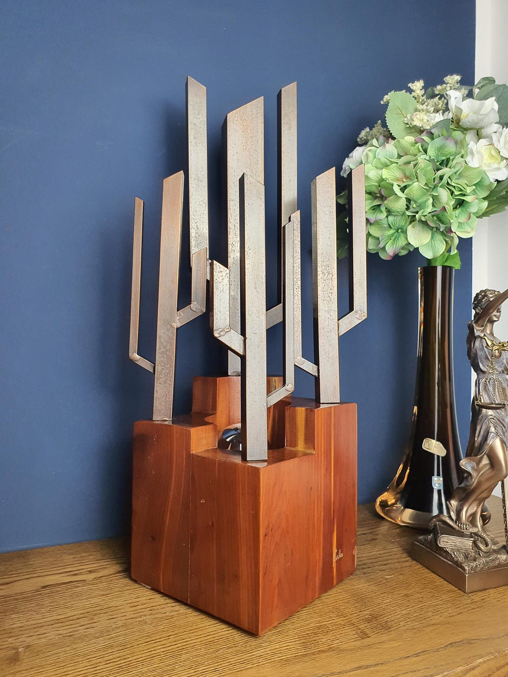 Carlo signed Brutalist table lamp front view, dark vertical metal rods rising from wooden cube base, 1970s Italy