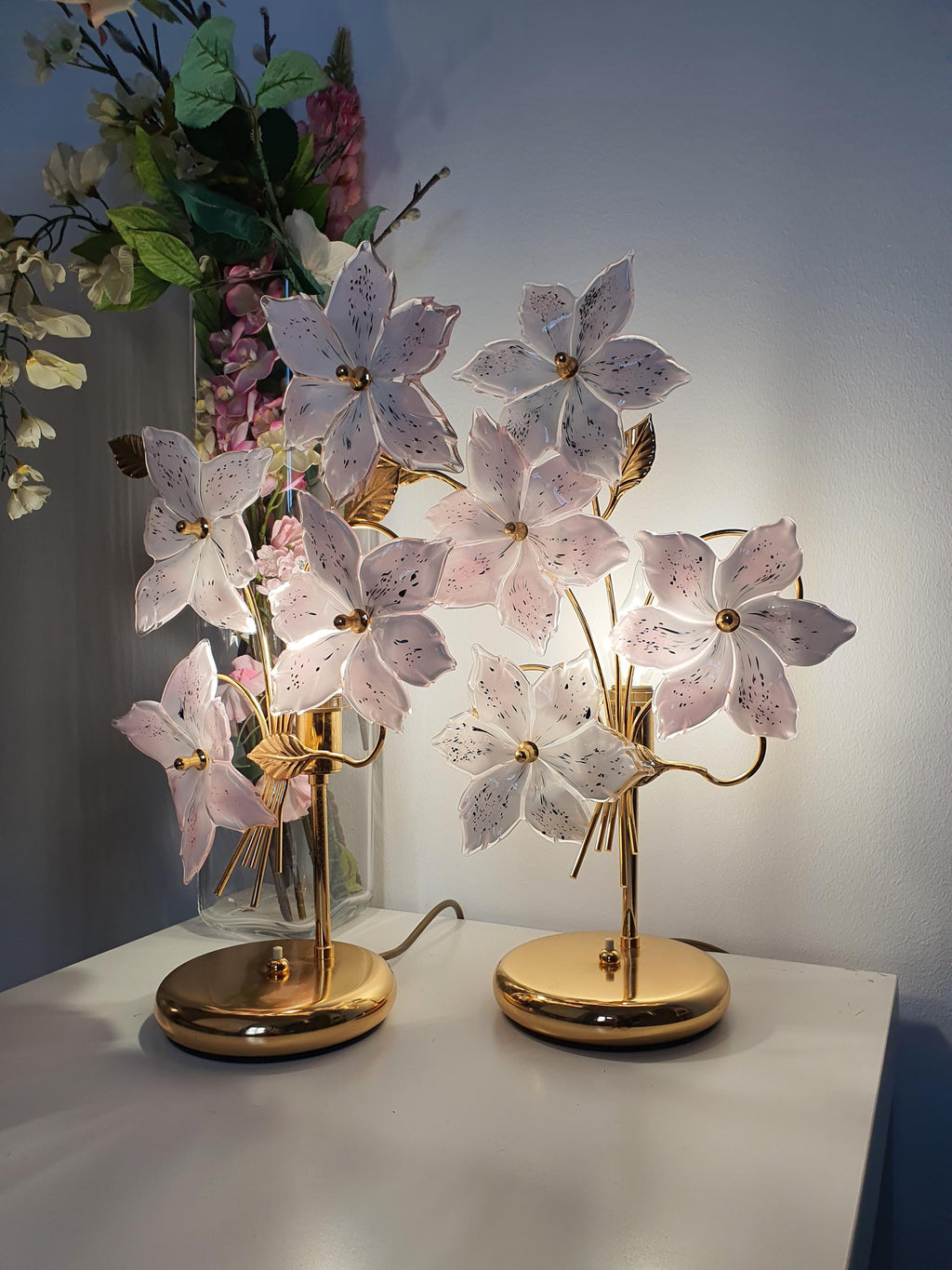 Sculptural glass flowers blooming outward from a gold-toned lamp base

