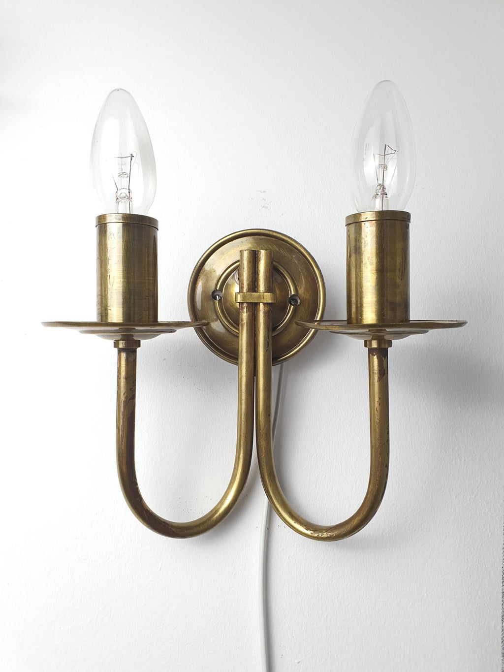 Vintage Italian double-arm lacquered brass wall sconce front view, two candle arms, natural brass patina, Art Deco silhouette
