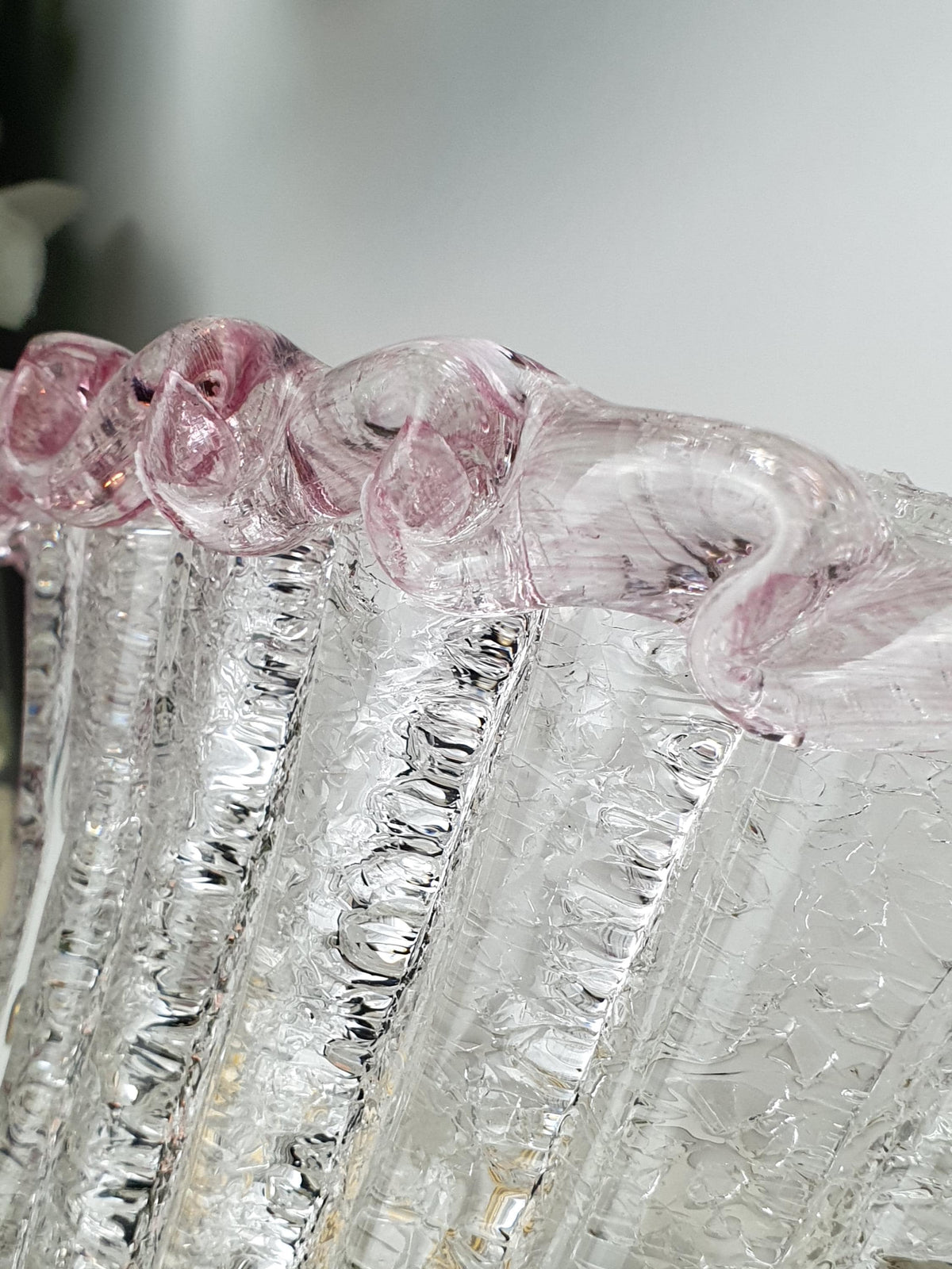Clear glass wall sconce with a delicate pastel pink border
