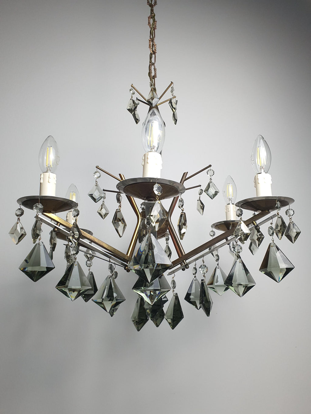Vintage Art Deco chandelier lit, dramatic smoky grey crystal reflections, warm candle glow, Hollywood Regency interior