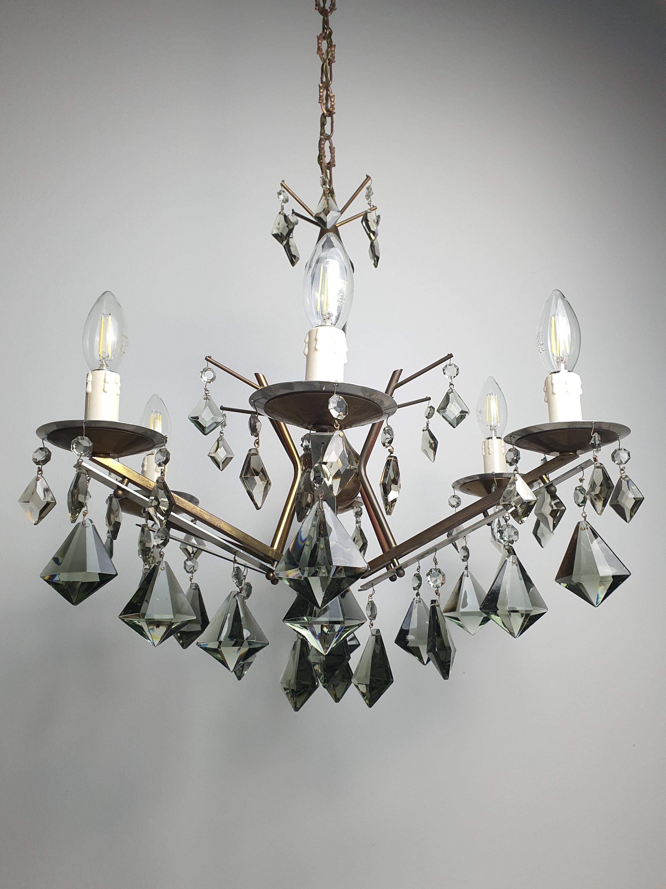 Vintage Art Deco chandelier lit, dramatic smoky grey crystal reflections, warm candle glow, Hollywood Regency interior