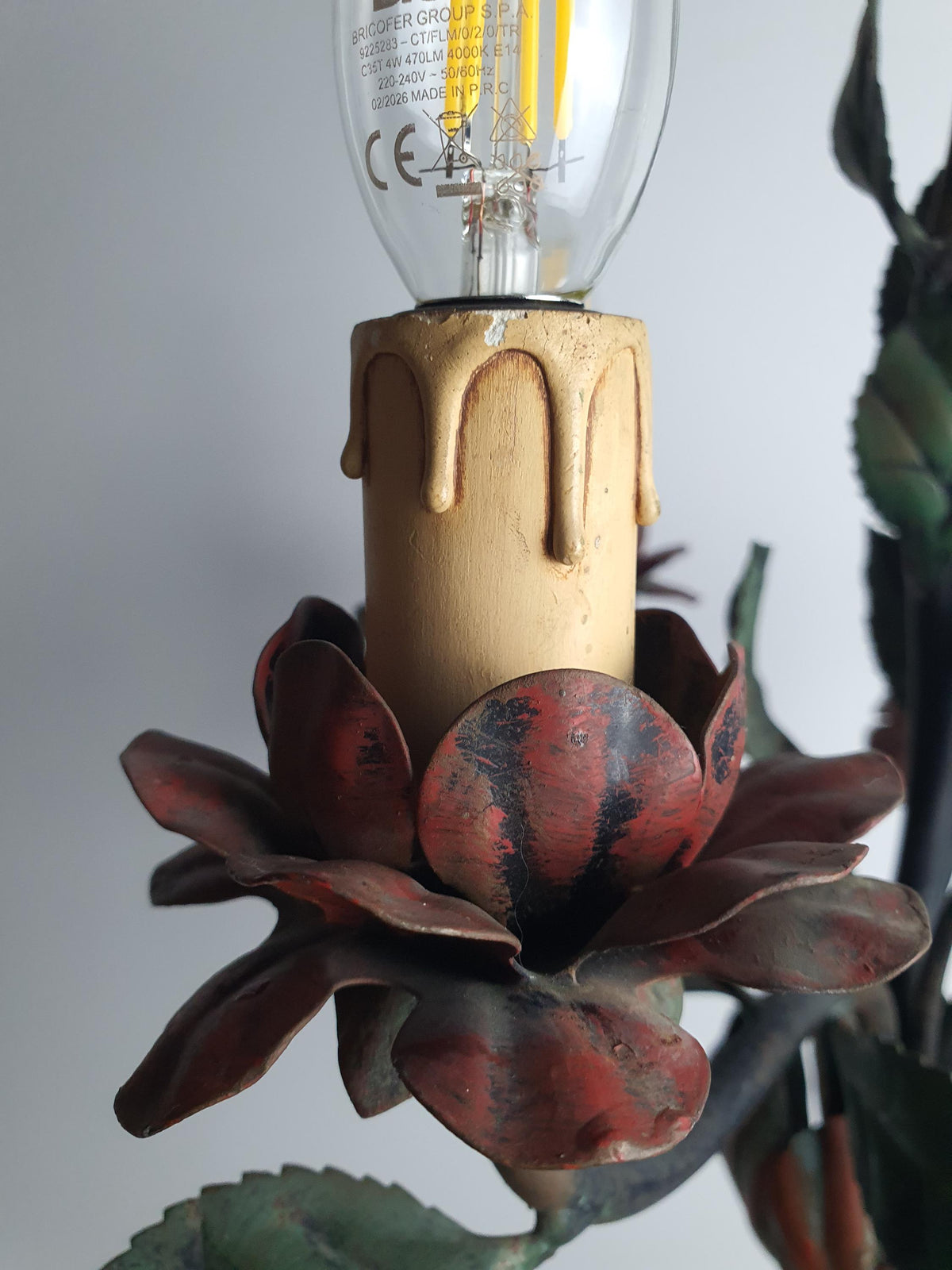 Decorative red flower details on a vintage three-arm tole chandelier
