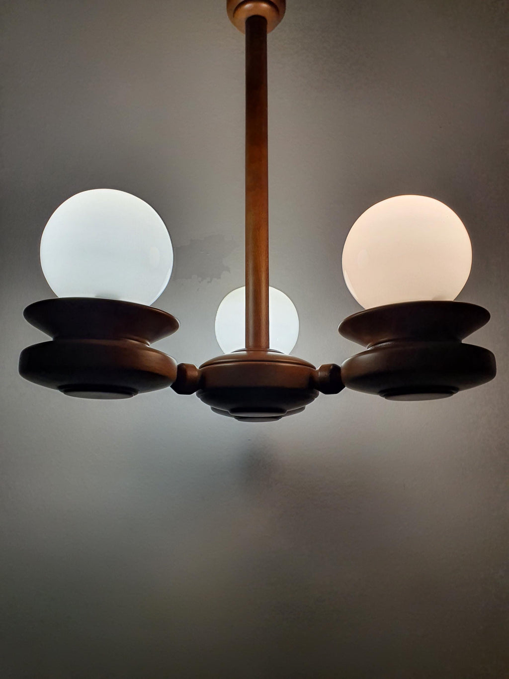 Vintage Space Age Sputnik chandelier lit, soft even milk glass globe glow, solid wood arms, warm Scandinavian MCM interior