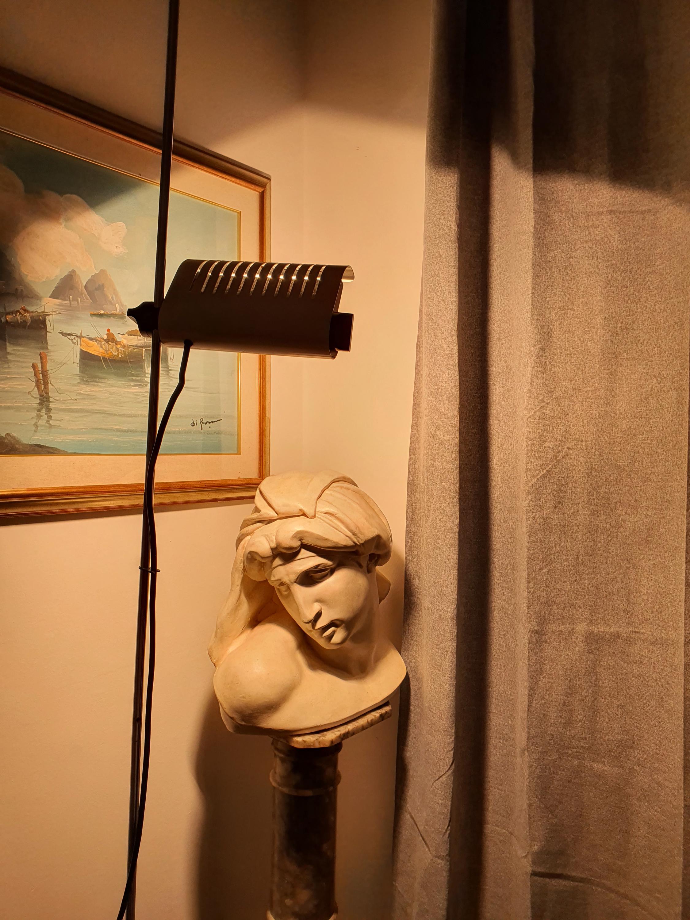Joe Colombo Model 626 floor lamp lit, directed upward light from white visor, warm ambient glow, Space Age design