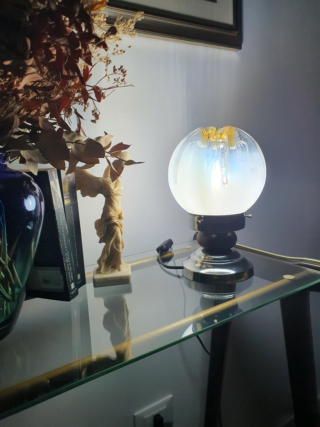 Vintage Mazzega Murano table lamp lit, warm amber glow through white-to-clear gradient globe, caramel drip relief reflections