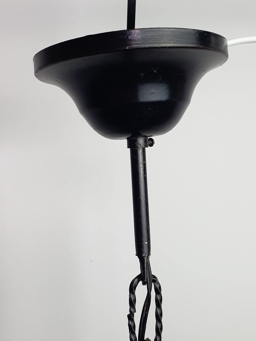 Black wrought iron frame detail on Mazzega style vintage Murano pendant, architectural forged metal structure, amber glass