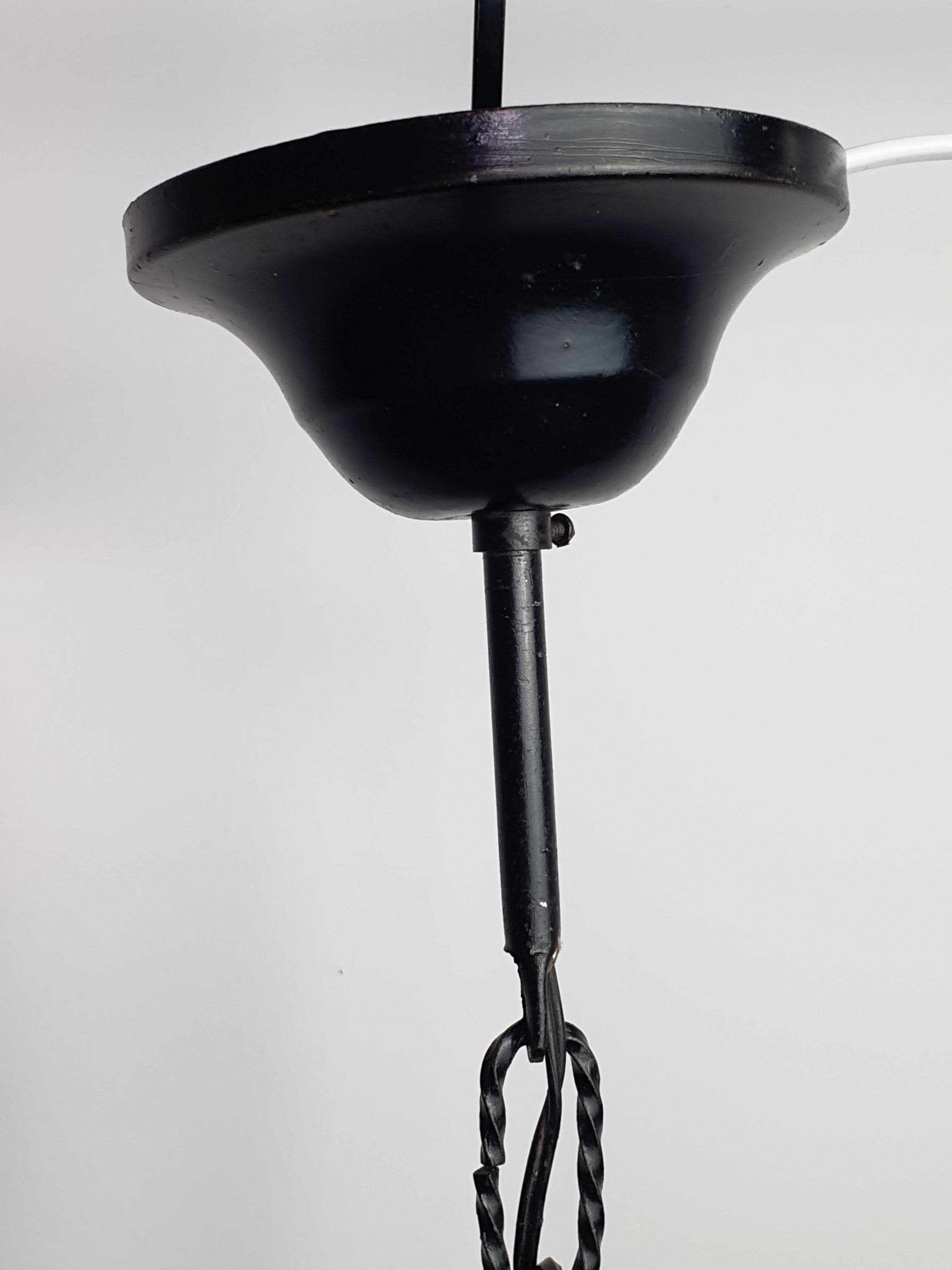Black wrought iron frame detail on Mazzega style vintage Murano pendant, architectural forged metal structure, amber glass
