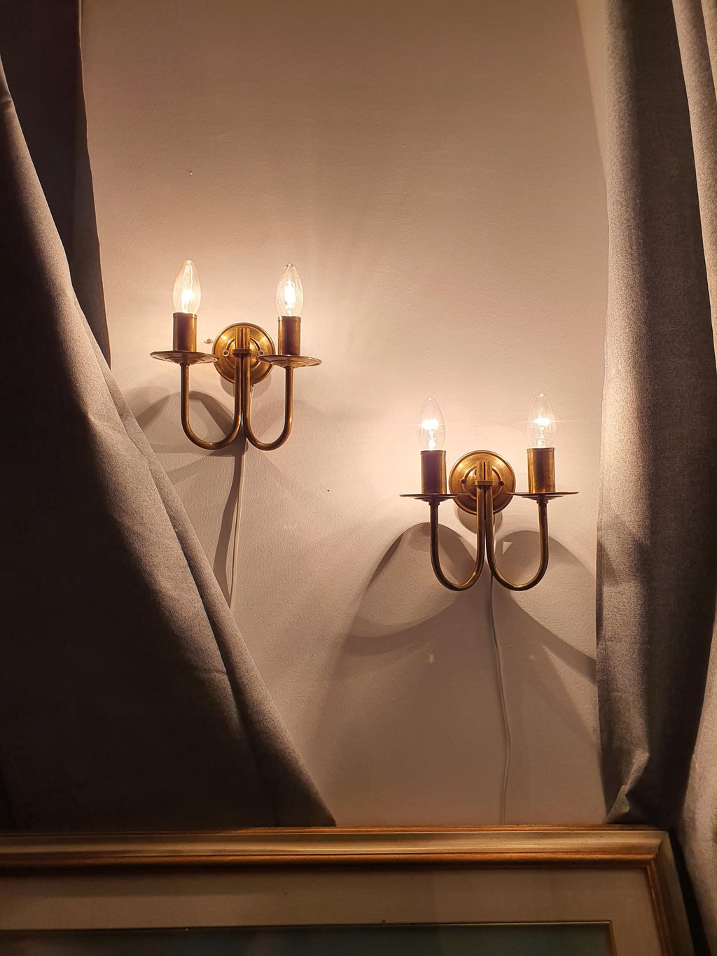 Pair of vintage Italian double-arm lacquered brass wall sconces framing fireplace, symmetrical pair, warm brass, Art Deco