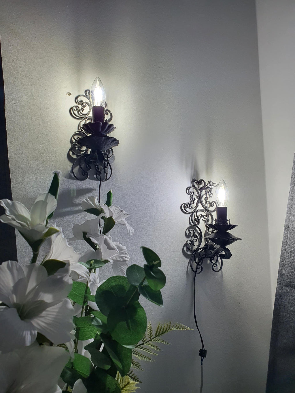 Gothic wrought iron wall sconce — illuminated, warm ambient glow, atmospheric lighting