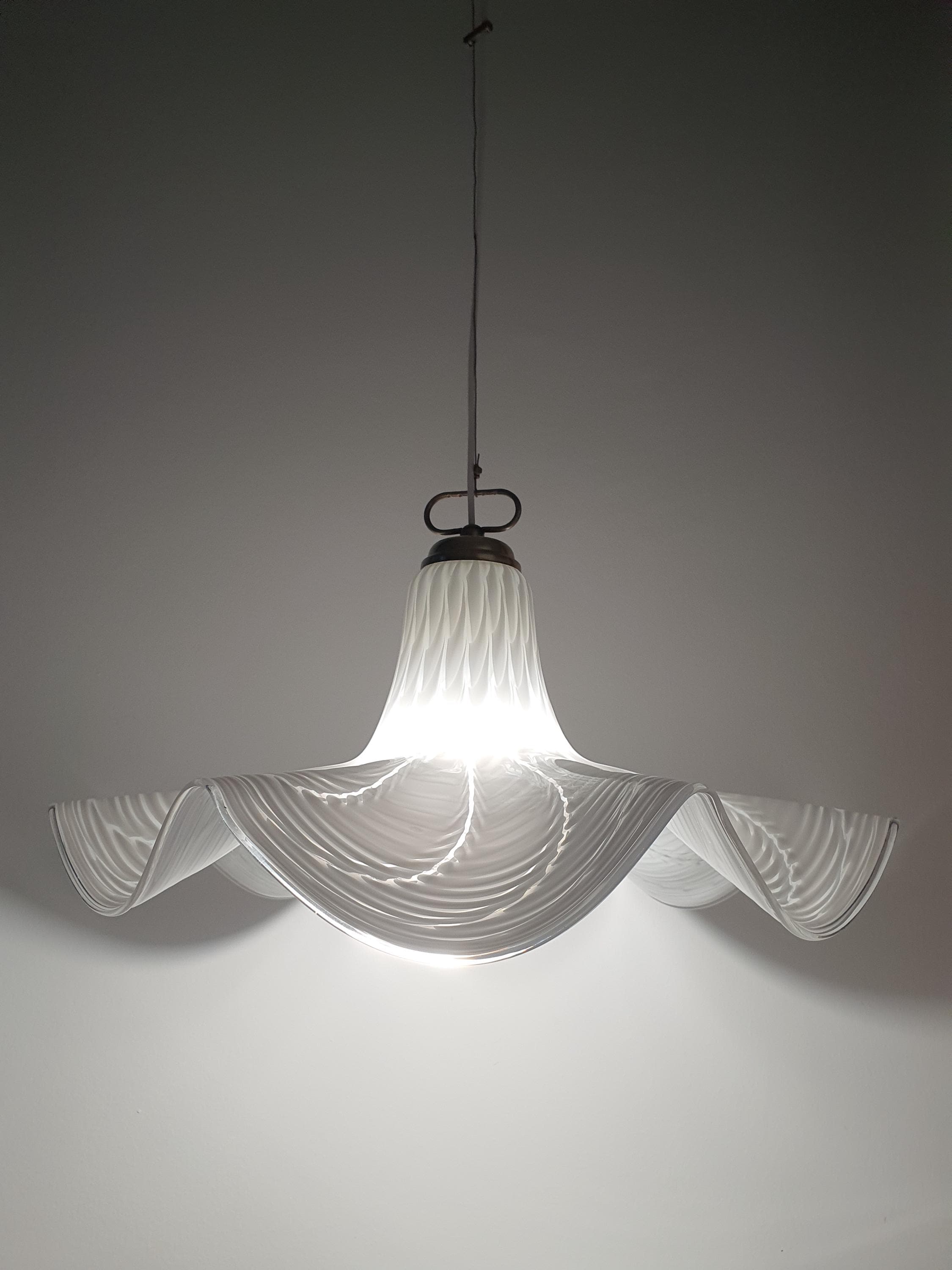Vintage Murano Fazzoletto pendant installed above dining table, soft organic form, warm glow